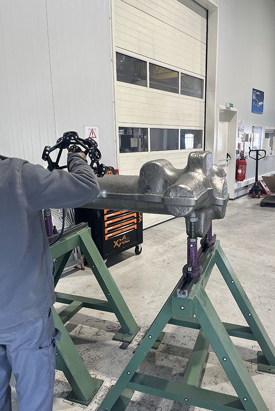 Un ouvrier numérise une pièce métallique en 3D avec la machine Metrascan